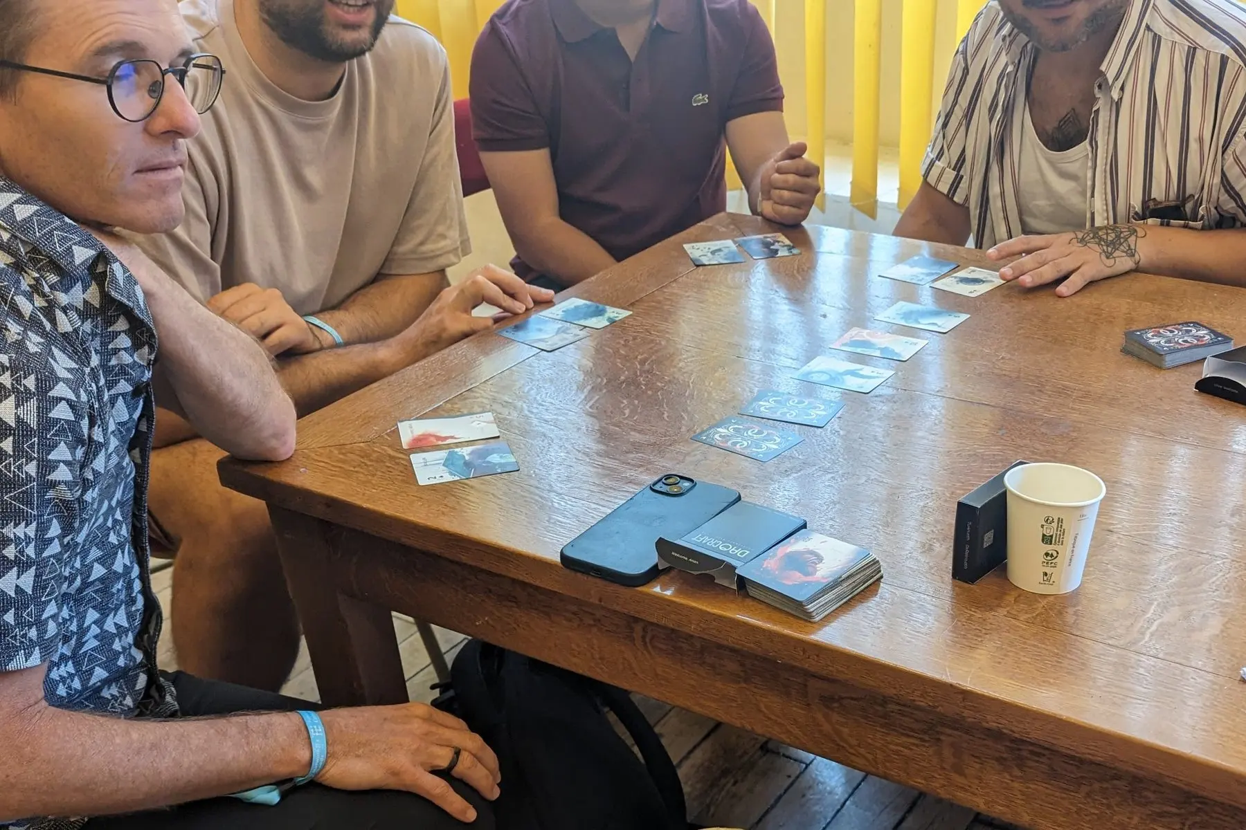 Players around a table in Paris, with cards from the deck face up between them.